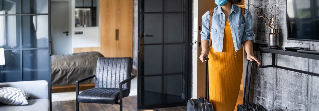 Beautiful afro woman with protective face mask arriving in hotel room